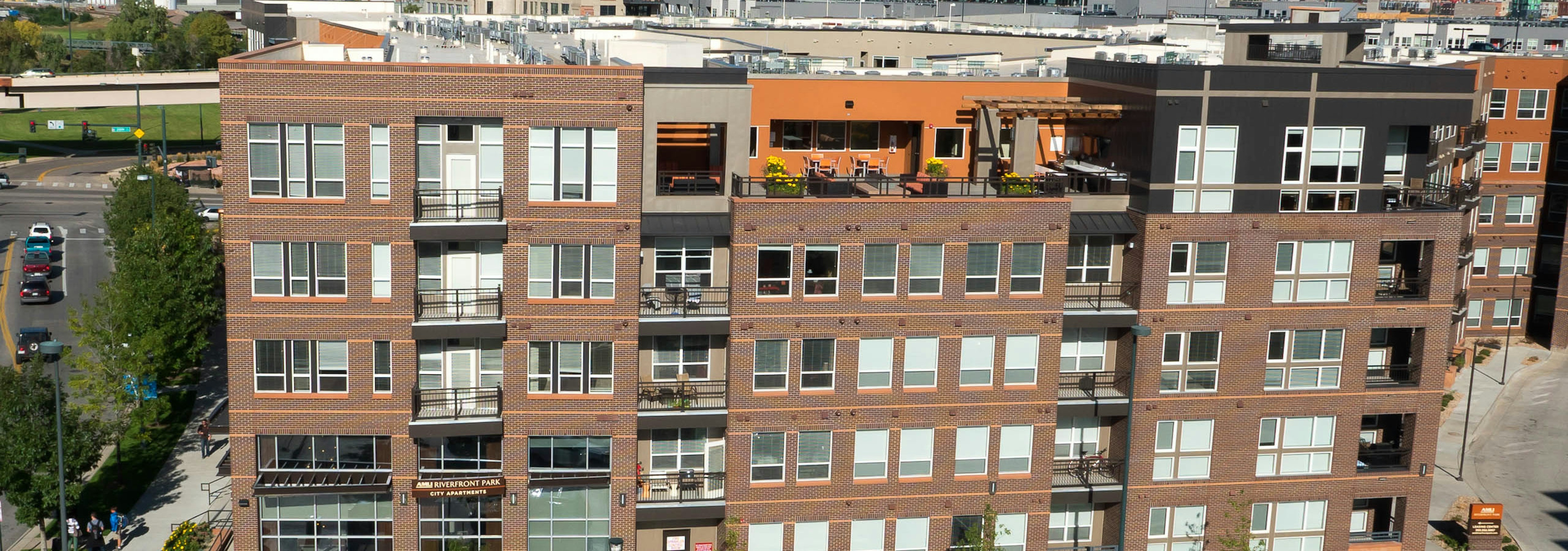 Aerial view of AMLI Riverfront Park apartments with brick facade and view of the rooftop lounge and windows and balconies 