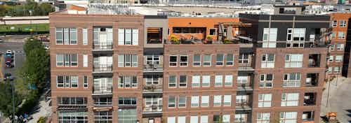 Aerial view of AMLI Riverfront Park apartments with brick facade and view of the rooftop lounge and windows and balconies