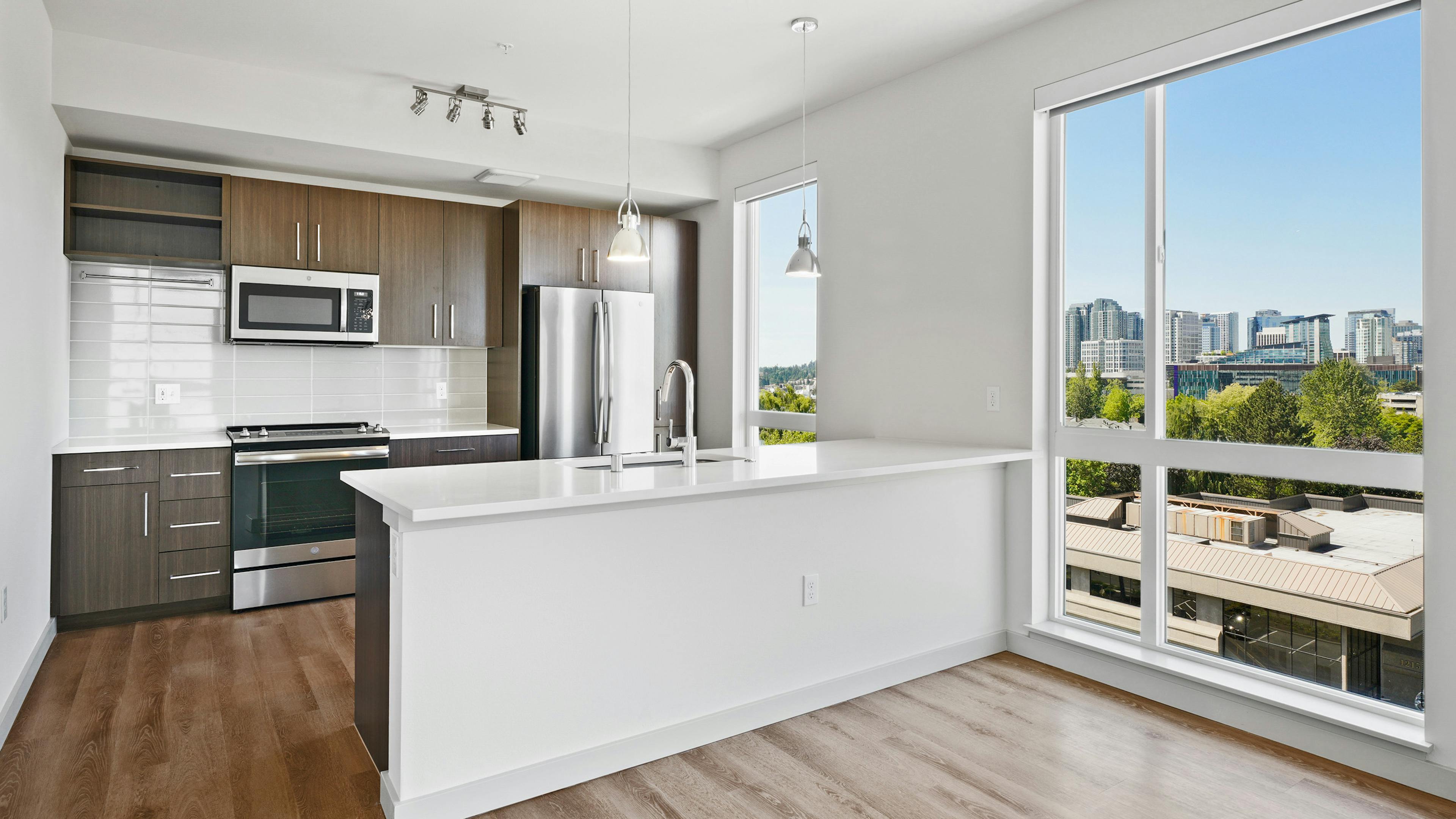 AML Spring District kitchen with dark cabinets and white backsplash and stainless steel appliances and Downtown Bellevue view
