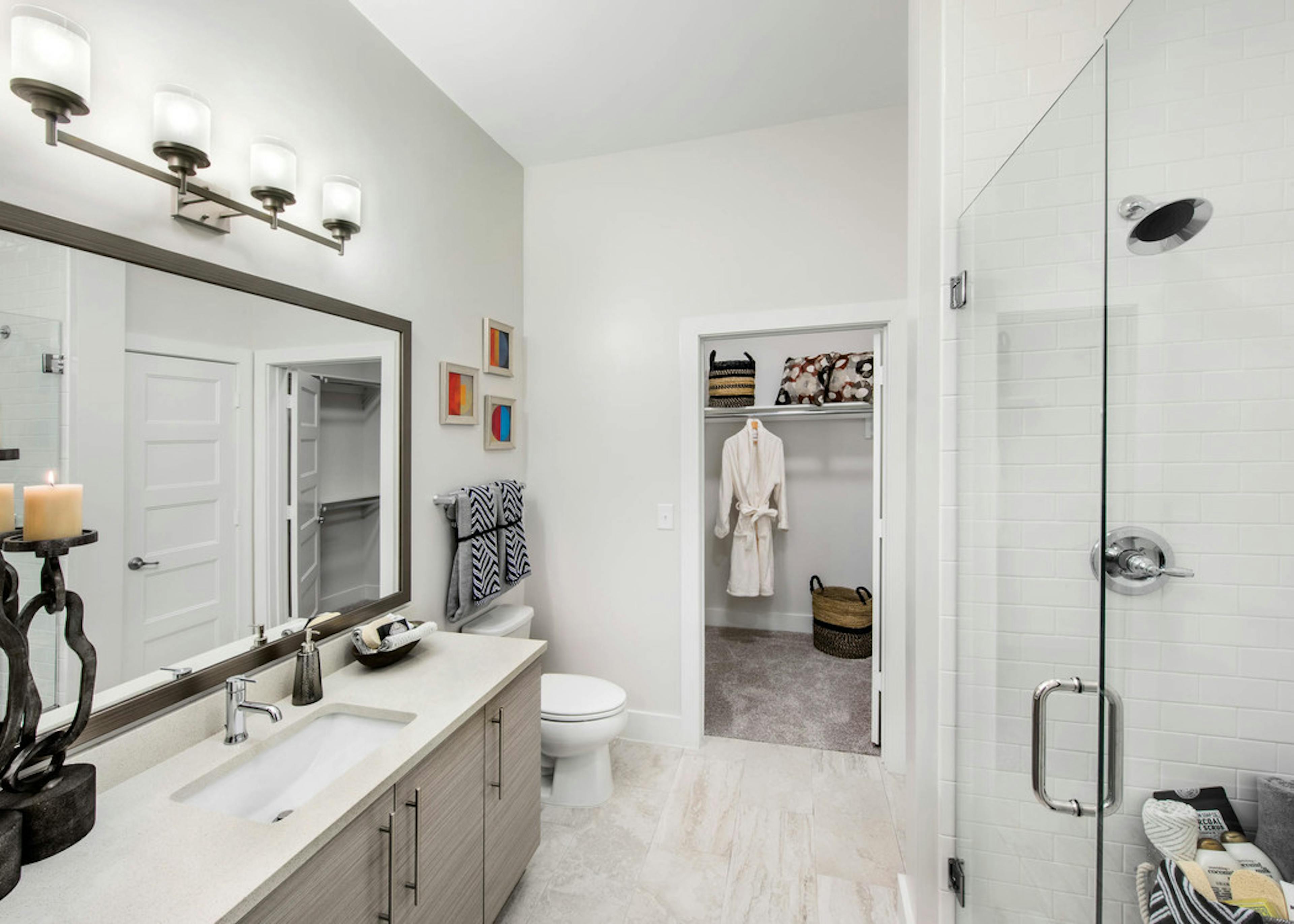 AMLI Buckhead bathroom with a vanity sink and clear glass door leading into the shower with walk in closet door peaking open