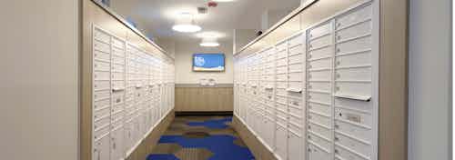 Interior view of the mail room at AMLI Dry Creek apartments with all resident mail boxes and carpeting and a television