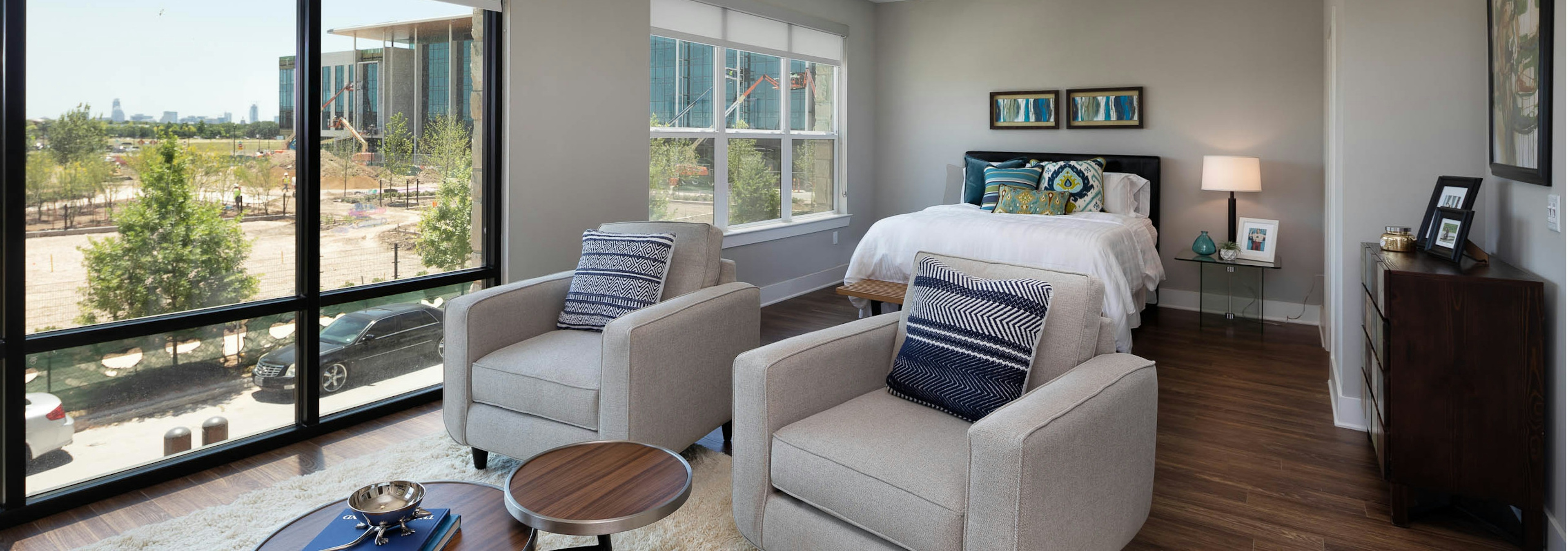 AMLI on Aldrich living room with two white chairs near floor to ceiling windows with dark wood floors and neutral walls