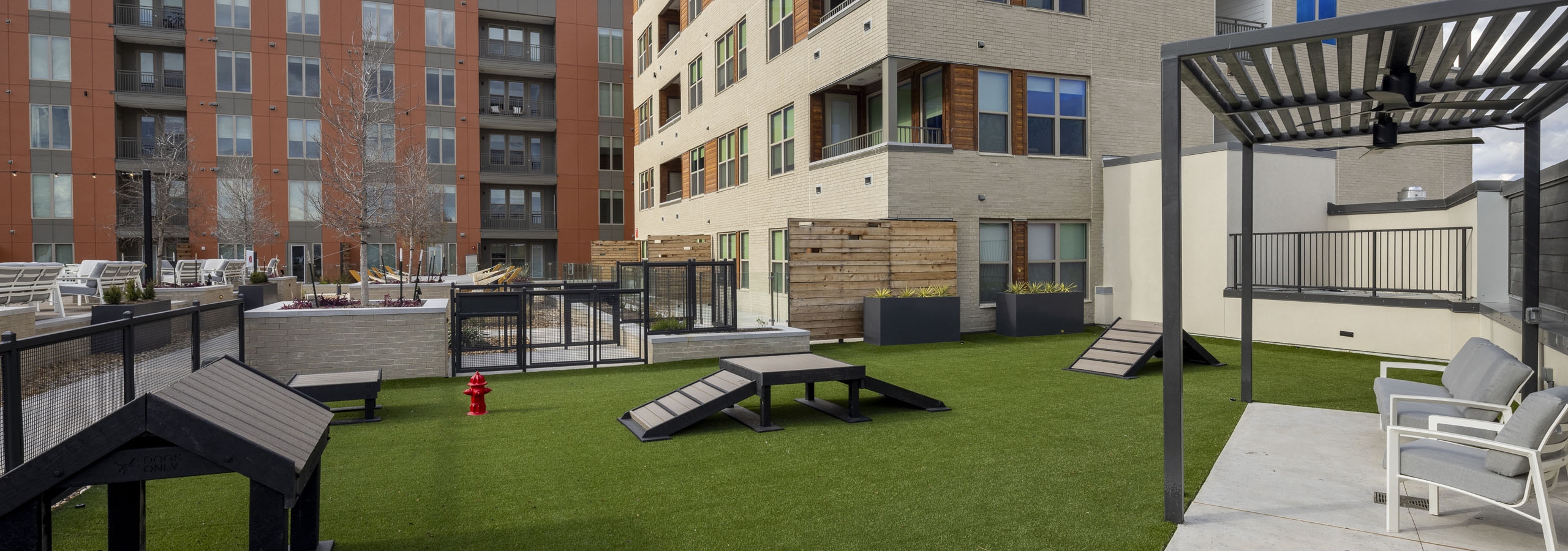 AMLI Branch Park  courtyard dog park featuring green artificial turf and dog play equipment adjacent to pool deck