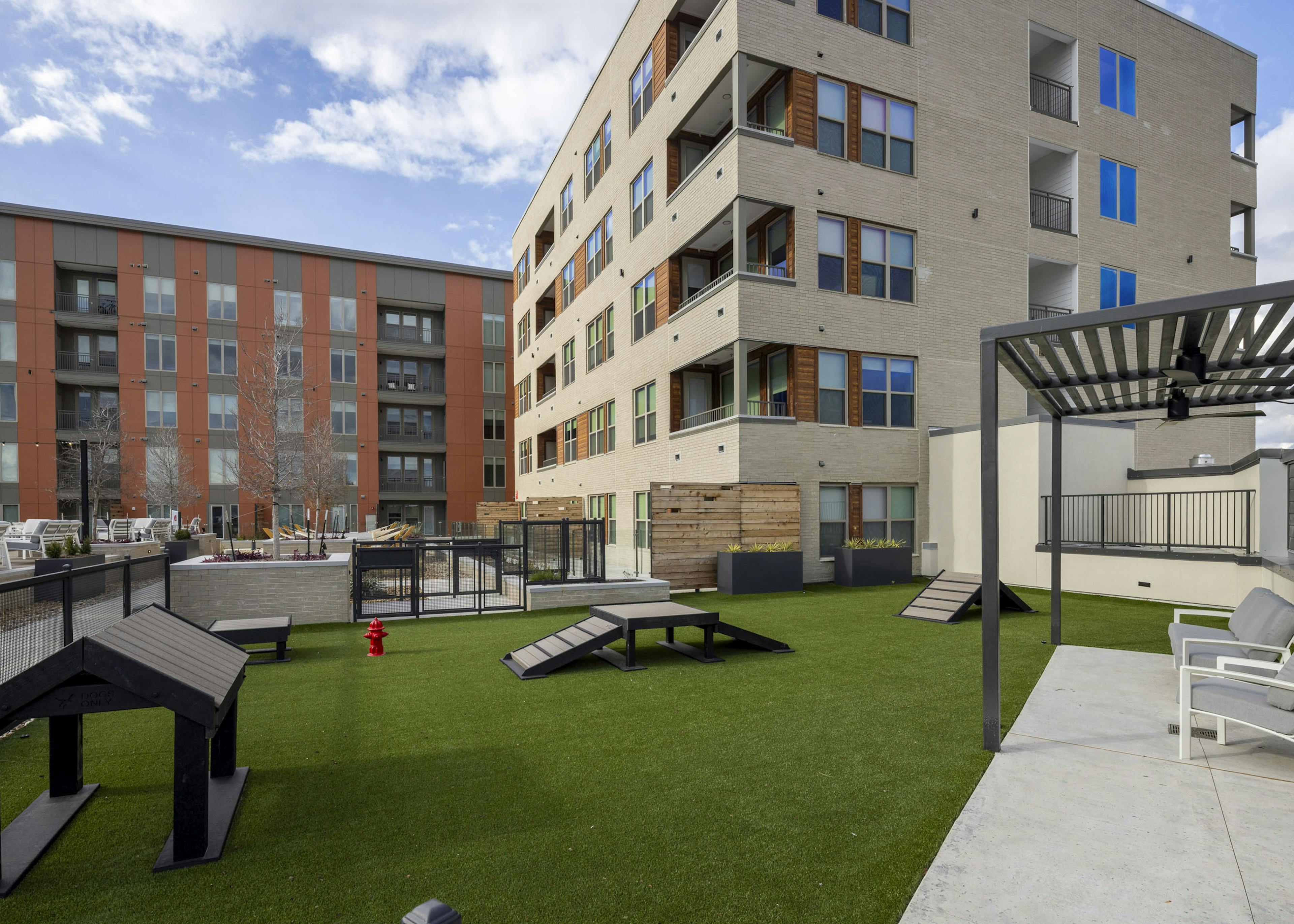 AMLI Branch Park  courtyard dog park featuring green artificial turf and dog play equipment adjacent to pool deck