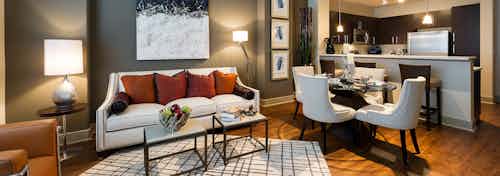 Interior view of AMLI River Oaks apartment living room with couch and coffee table into dining room and kitchen