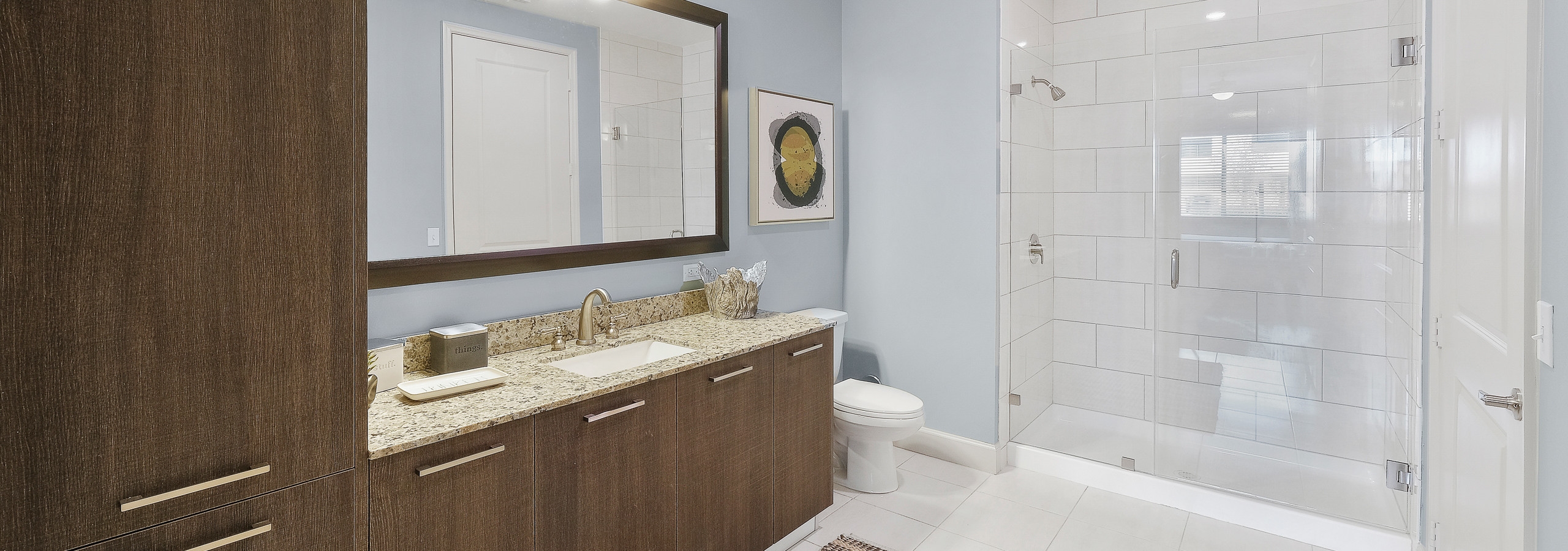 AMLI 8800 apartment bathroom with large single sink vanity, mirror, toilet and stand up glass enclosed shower