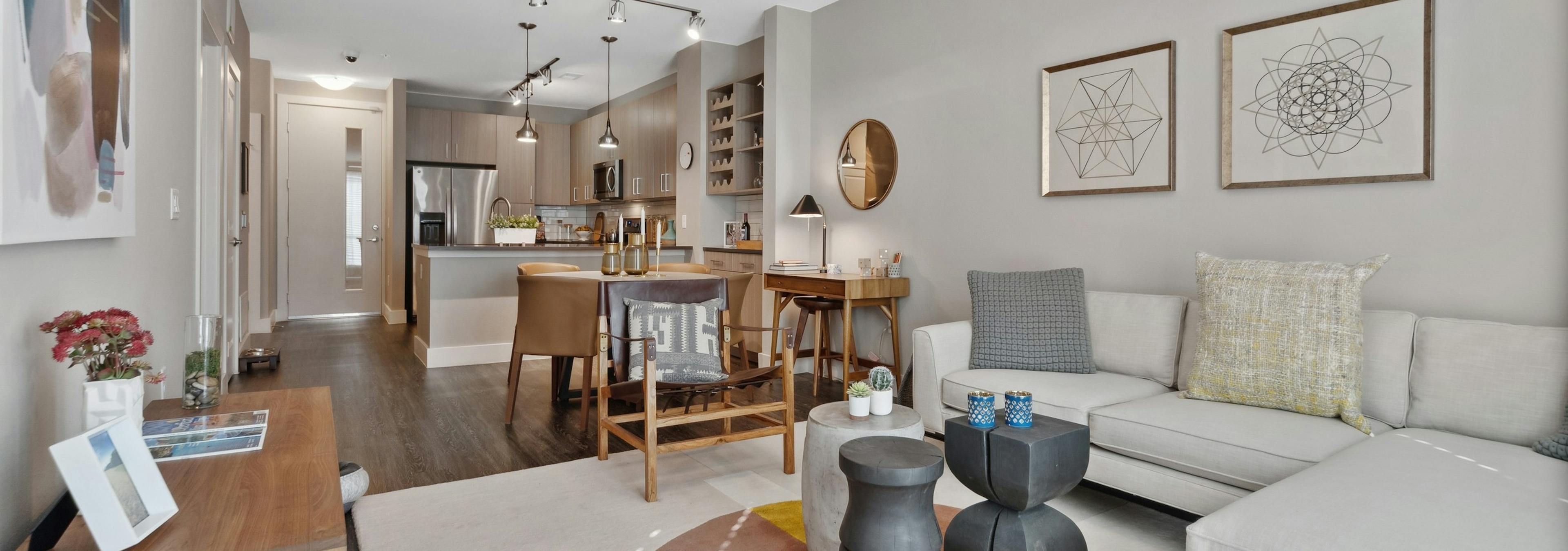 Living and dining room at AMLI Dry Creek apartments featuring a sectional couch and dining table with kitchen in rear