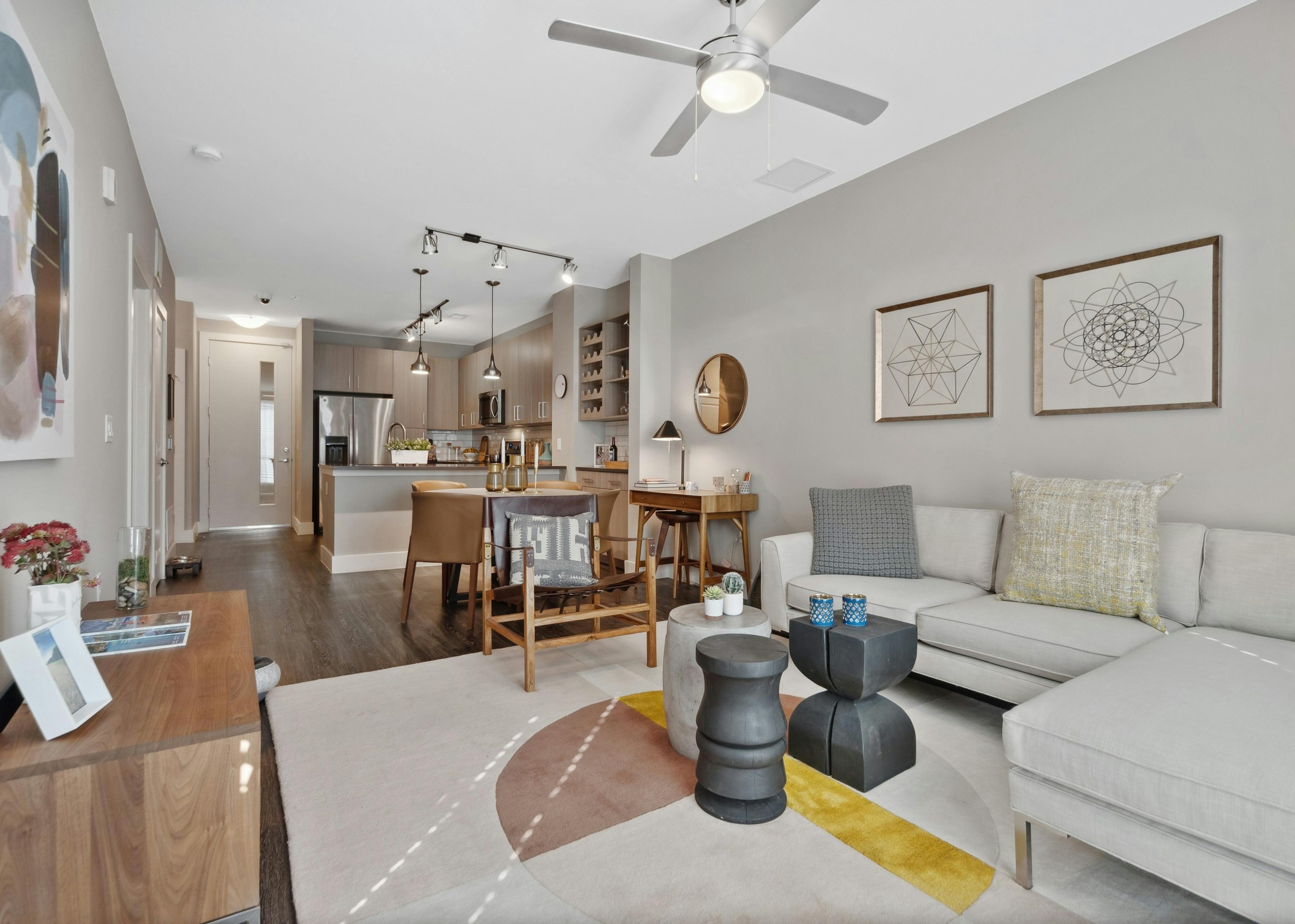 Living and dining room at AMLI Dry Creek apartments featuring a sectional couch and dining table with kitchen in rear