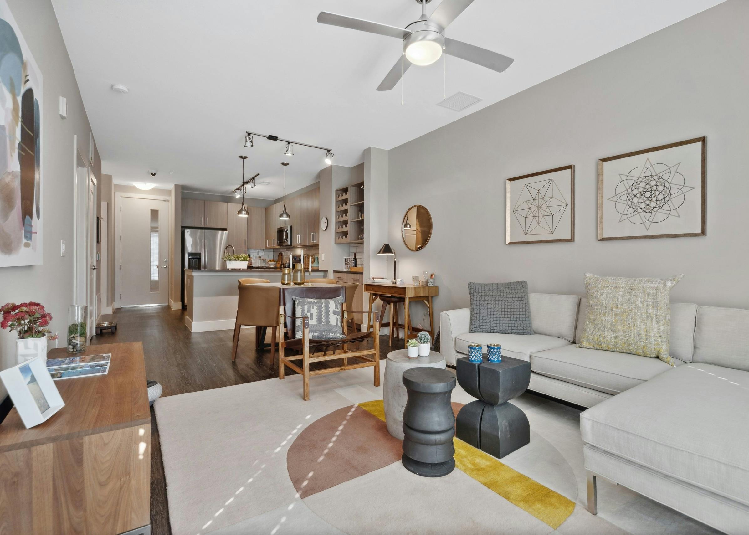 Living and dining room at AMLI Dry Creek apartments featuring a sectional couch and dining table with kitchen in rear
