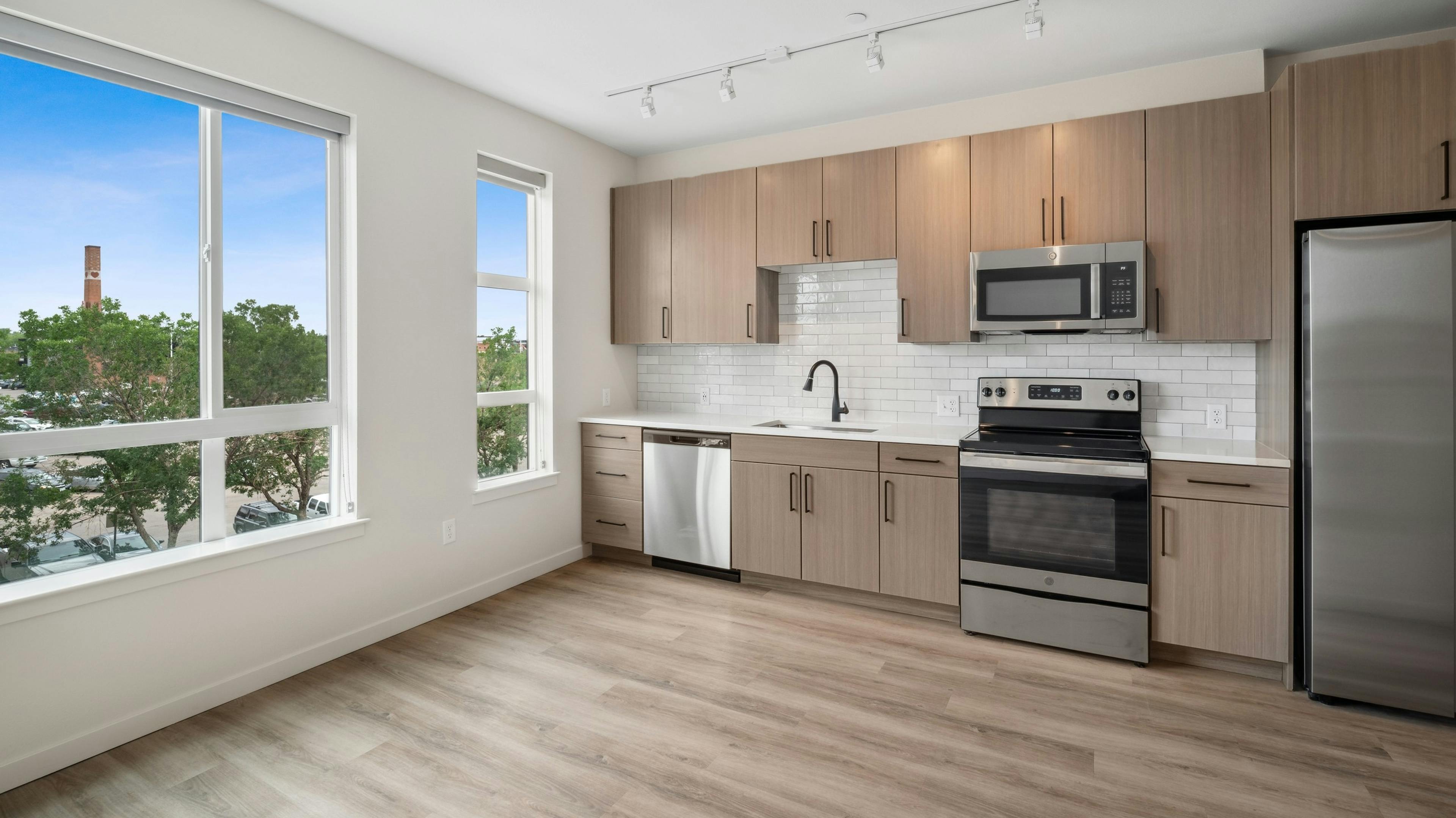 Kitchen with city view and woodgrain cabinets with stainless steel appliances at AMLI Broadway Park apartments