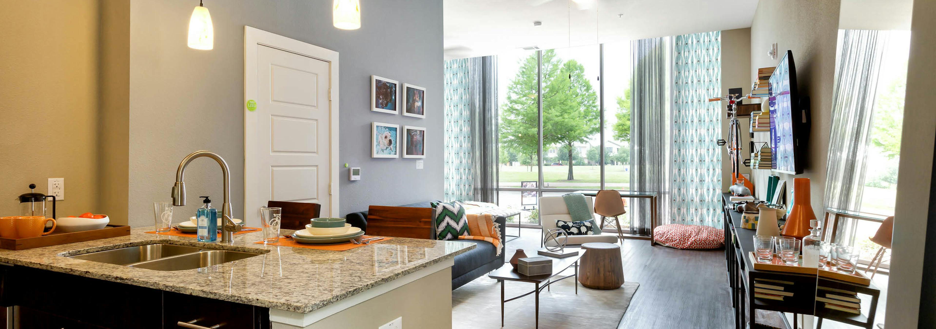 Interior of AMLI at Mueller living room with dark floors and floor to ceiling windows with colorful decor and light walls