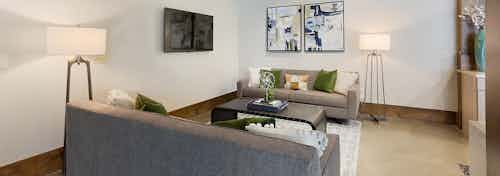 AMLI Old 4th Ward renovated clubroom with multiple grey couches facing one and other with large windows for natural sunlight