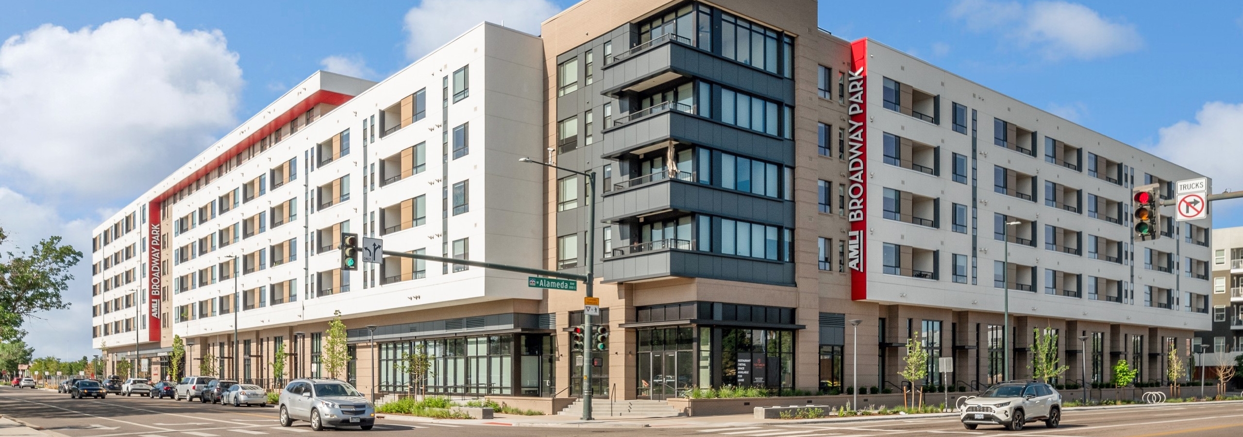 Exterior view of AMLI Broadway Park apartment building with grey and tan and brown exterior overlooking the street with cars