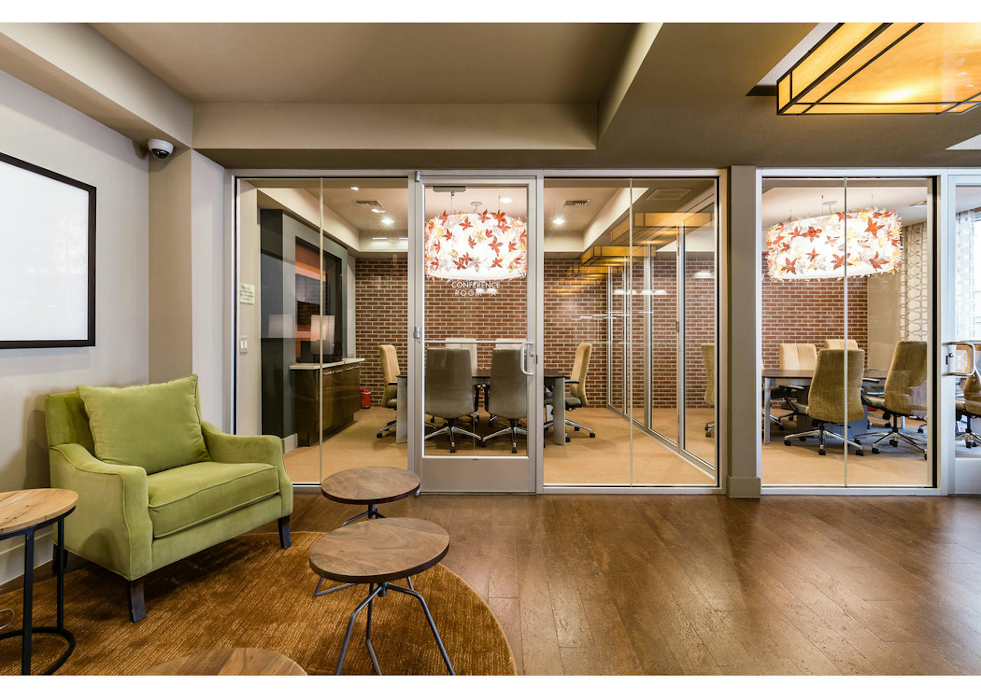 Interior view of AMLI RidgeGate conference rooms equipped with large tables and chairs, ornate chandelier and faux brick wall