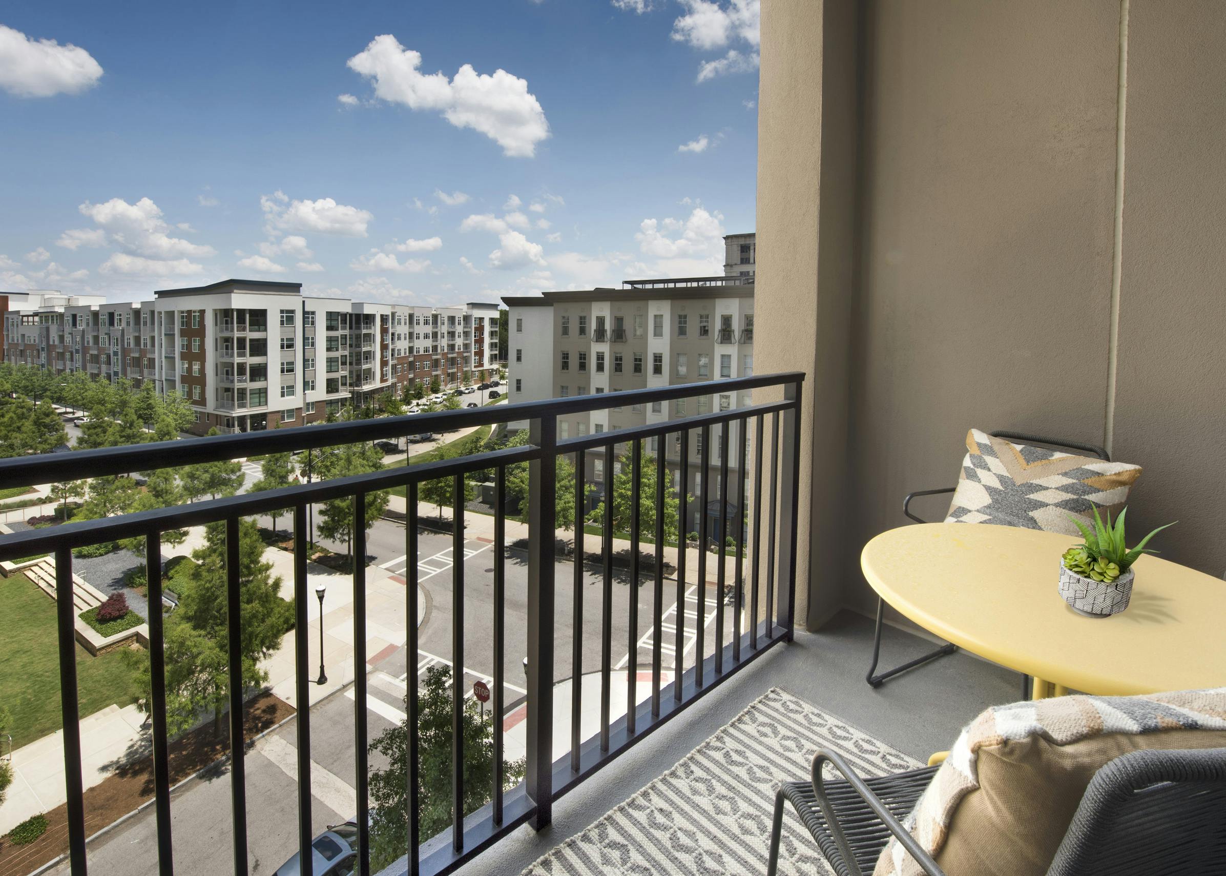 Exterior view of balcony at AMLI Lenox with table and two chairs overlooking Marie Sims Park and AMLI Buckhead