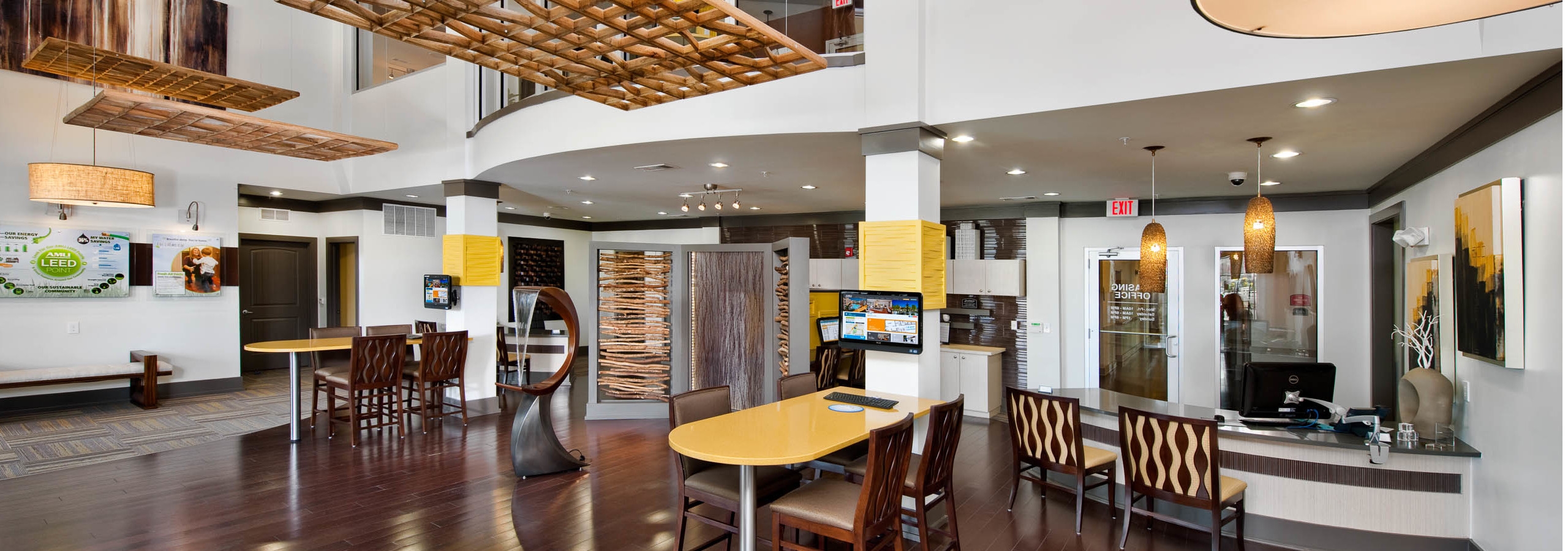 Interior of AMLI North Point leasing office with shiny dark wood floors and mustard yellow light fixtures and decor