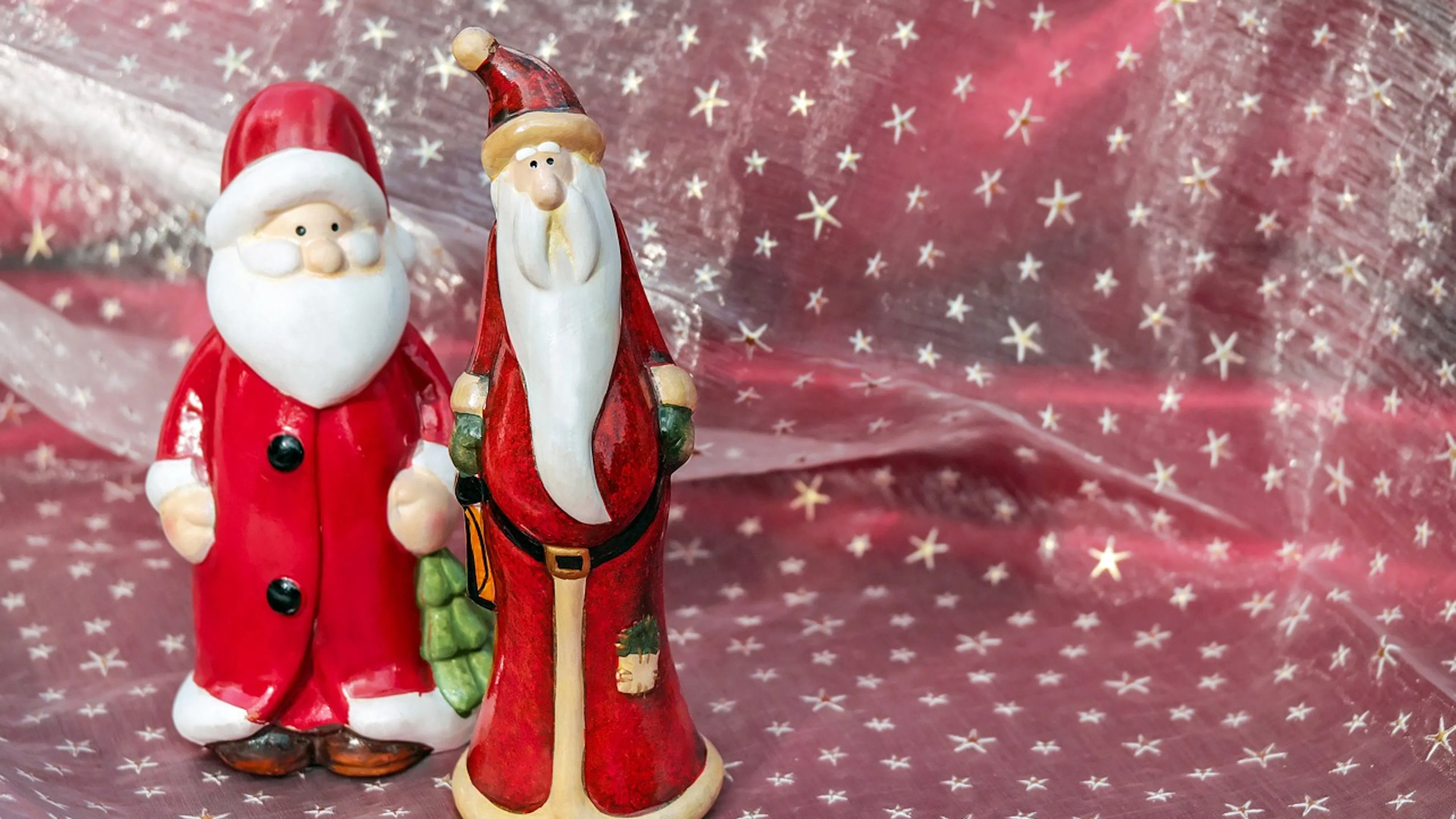 Two small Santa Claus statues on a snowflake tablecloth