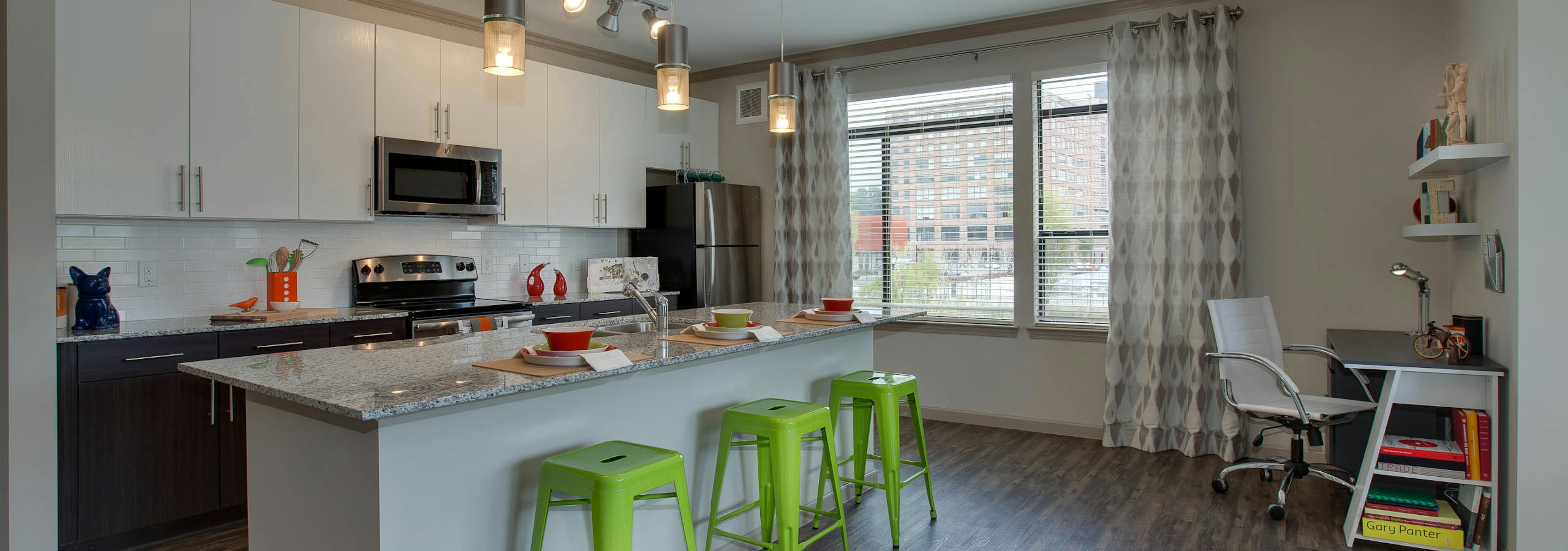 Interior view of AMLI Ponce Park apartment island kitchen with stainless steel appliances and white wood cabinetry