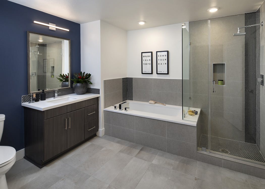 Interior of AMLI Marina Del Rey apartment bathroom with free standing shower with frameless doors and tub and tile surround