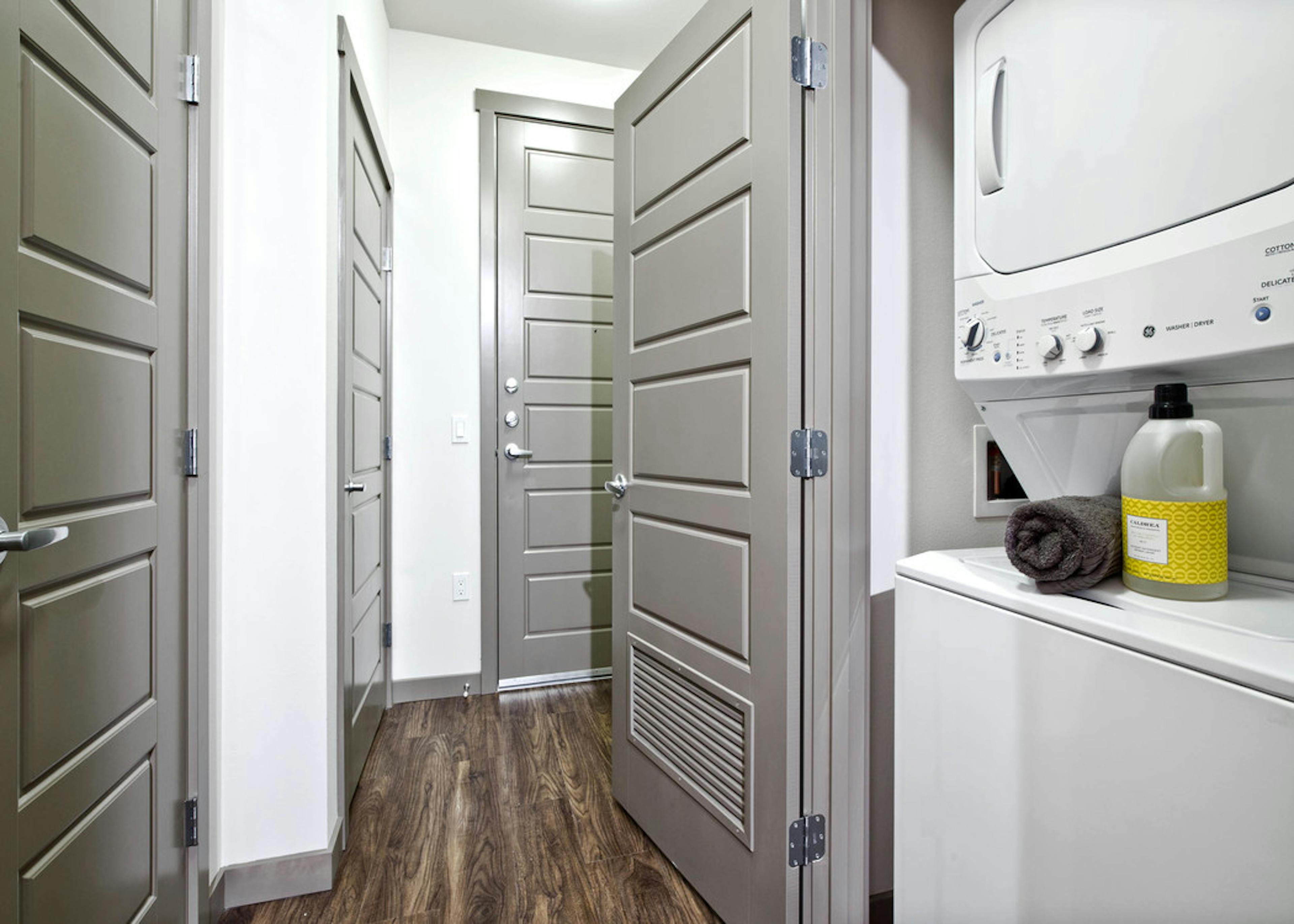 Interior view of stackable washer and dryer at AMLI Mark24 apartment with view of front entrance 