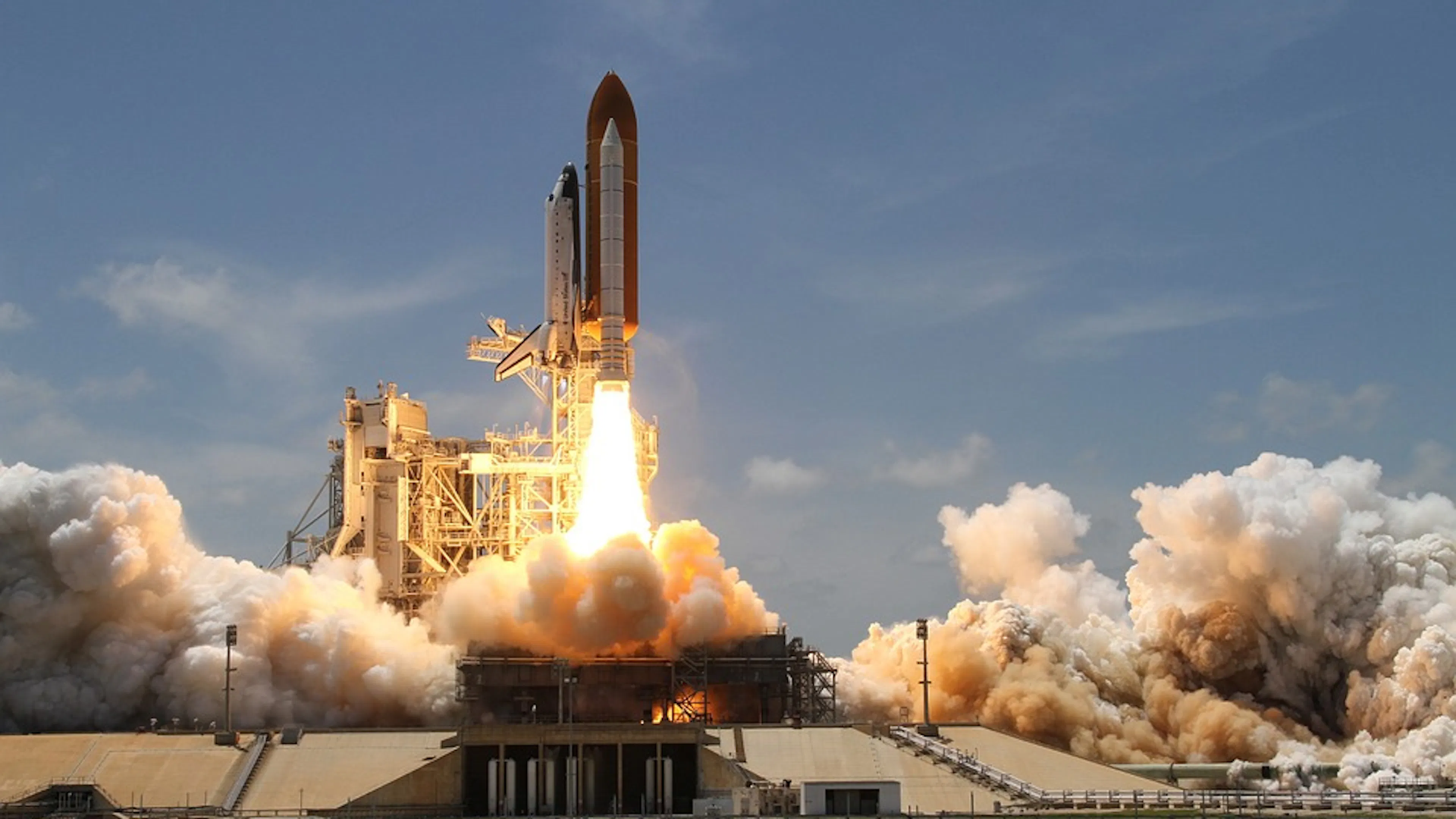 A rocket launching into space on a clear day with smoke bursting from the engine
