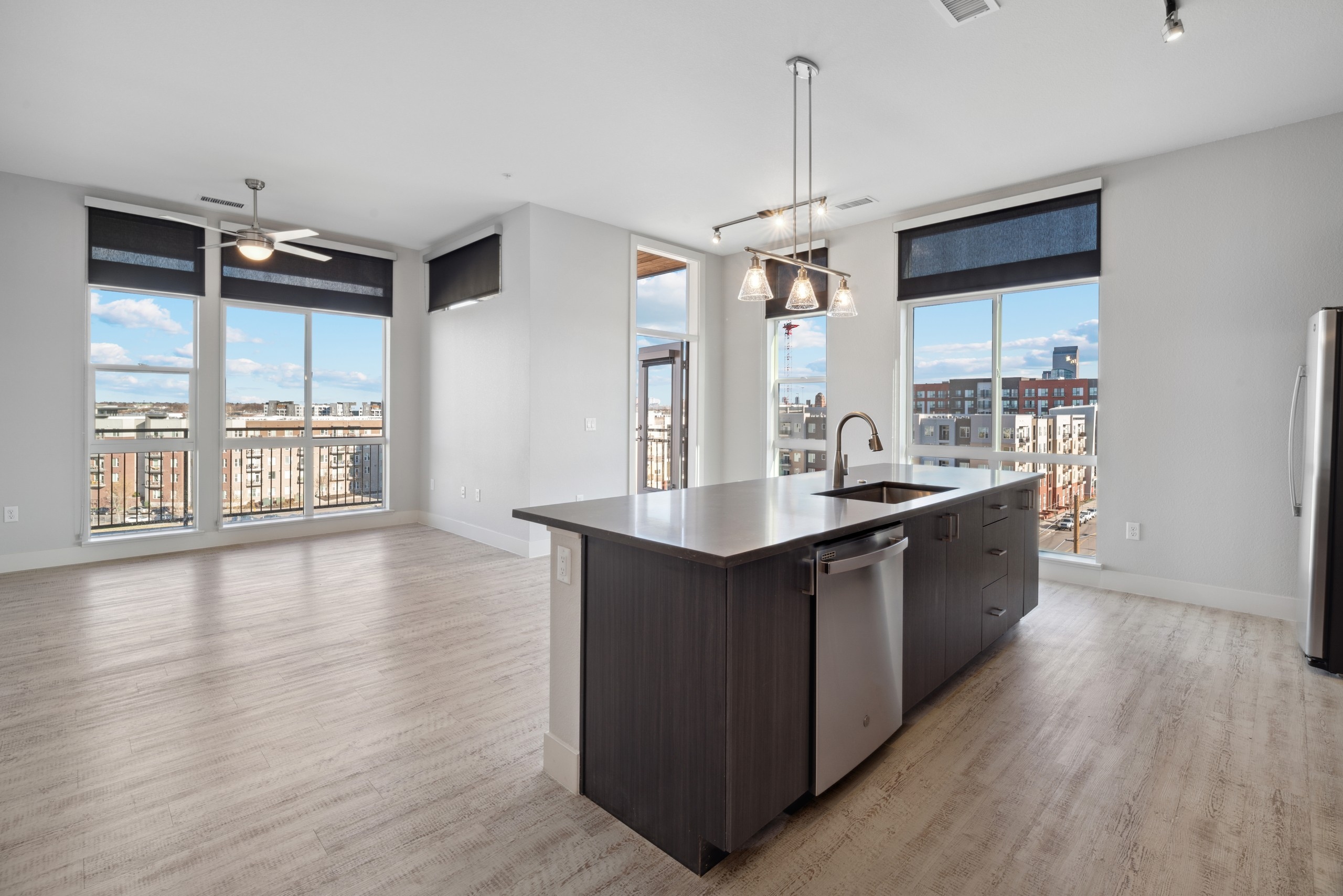 Kitchen with brown woodgrain cabinets and  stainless steel appliances and silver pendant and track lighting at AMLI RiNo