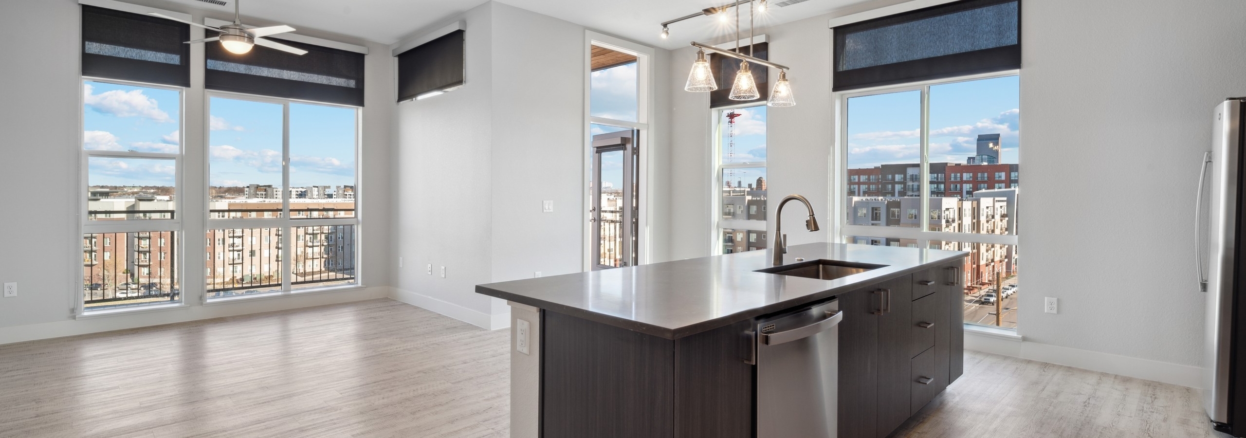 Kitchen with brown woodgrain cabinets and  stainless steel appliances and silver pendant and track lighting at AMLI RiNo