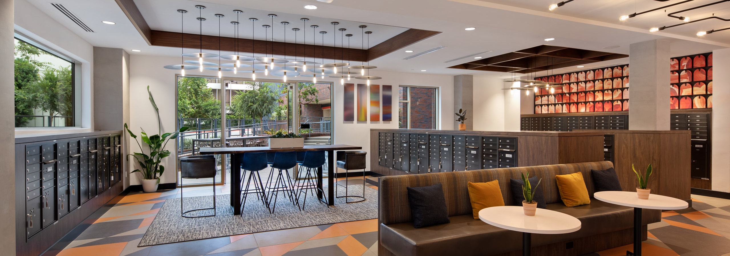 Daytime view of mail room lounge with beautiful decorative pendant lighting over workspaces at AMLI Old Pasadena apartments