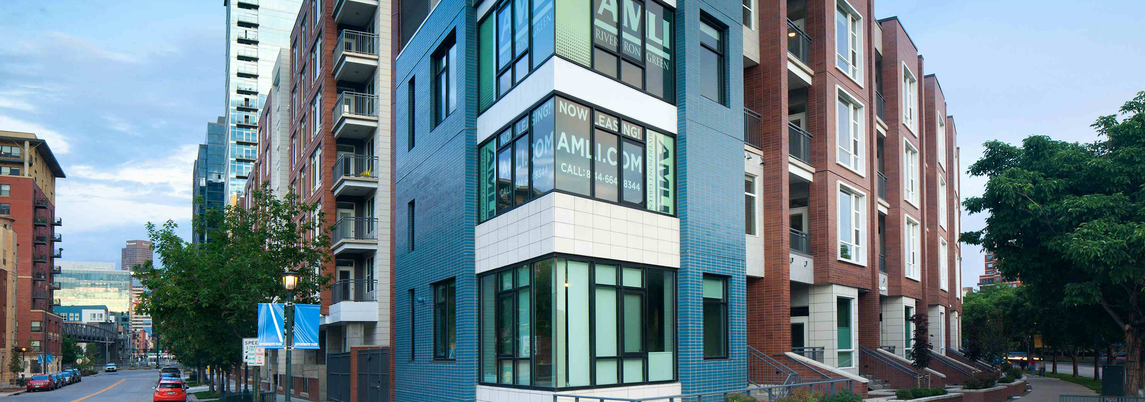 Day time view of the exterior of AMLI Riverfront Green apartments with view of surrounding buildings as well as side streets