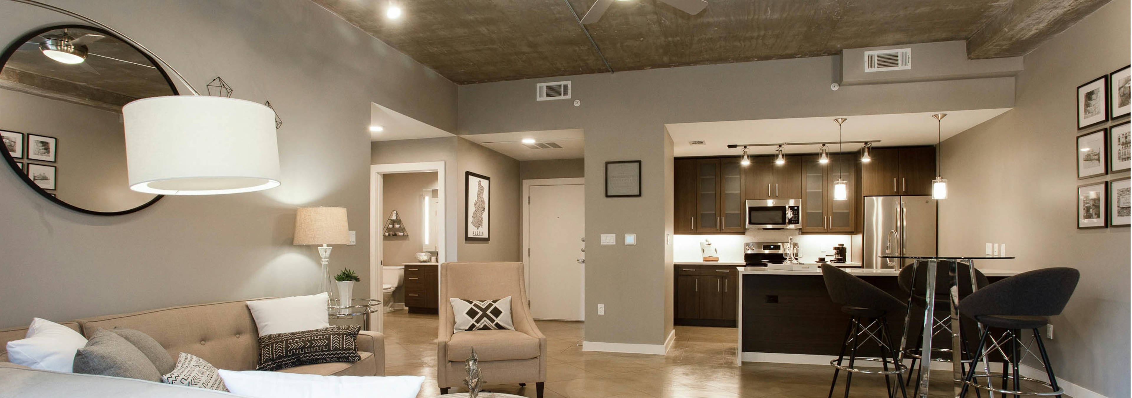 Living room at AMLI Downtown with hardwood flooring leading into the kitchen with an open door peeking into bedroom