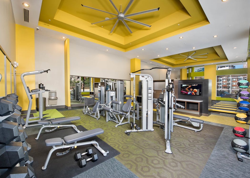 Interior of spacious AMLI Buckhead fitness center with a variety of weight machines with yellow walls and grey flooring