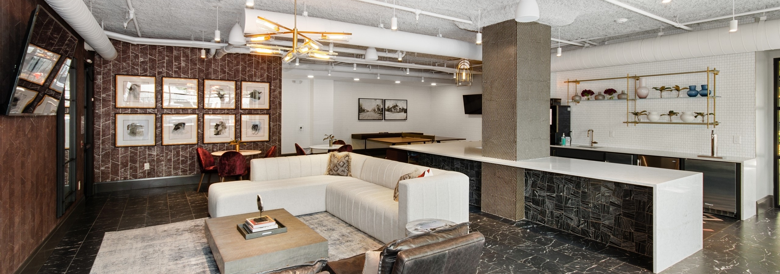 Resident lounge at AMLI Quadrangle apartments with a lounge area facing a wall mounted TV and a large resident kitchen