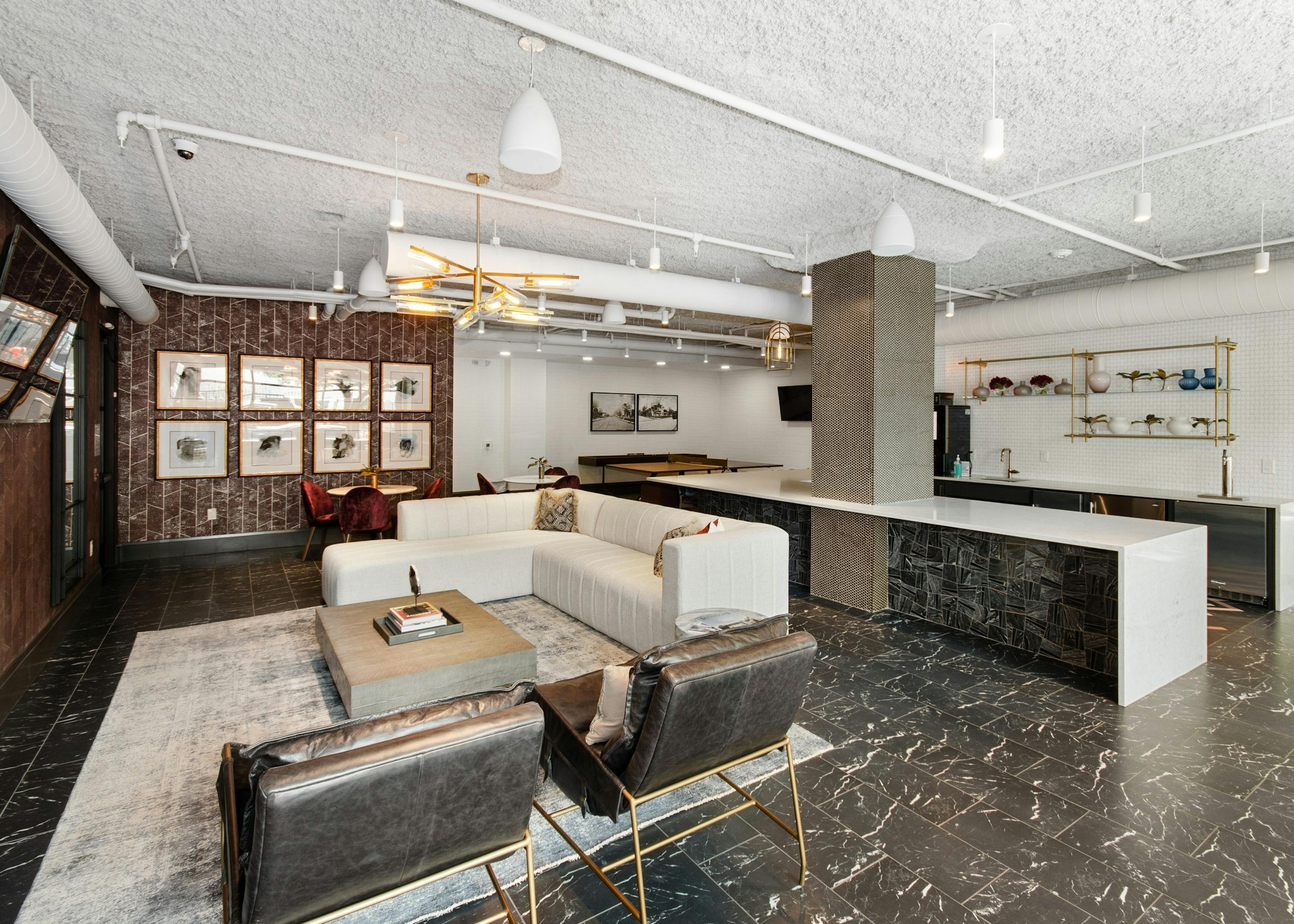 Resident lounge at AMLI Quadrangle apartments with a lounge area facing a wall mounted TV and a large resident kitchen