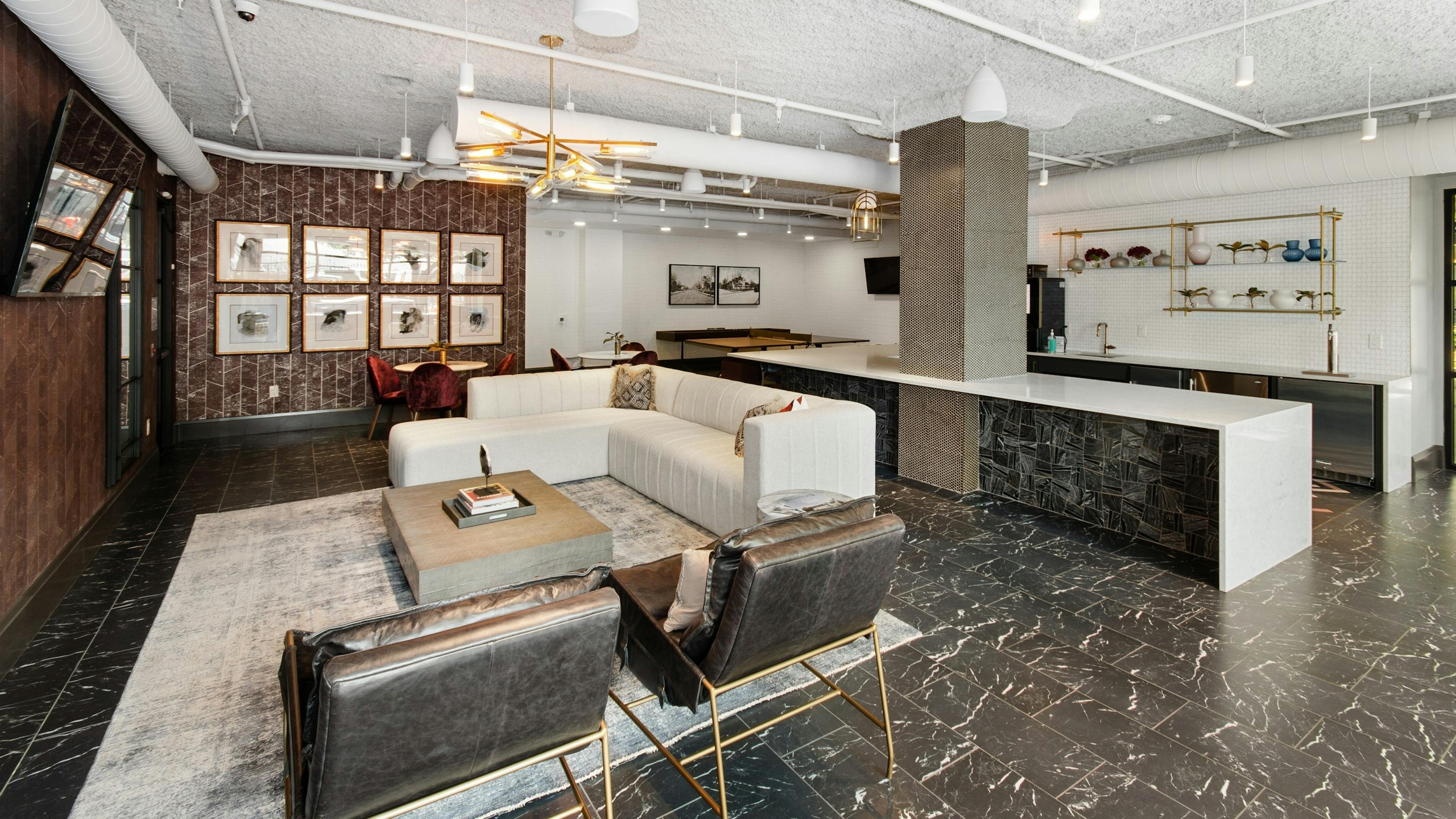 Resident lounge at AMLI Quadrangle apartments with a lounge area facing a wall mounted TV and a large resident kitchen