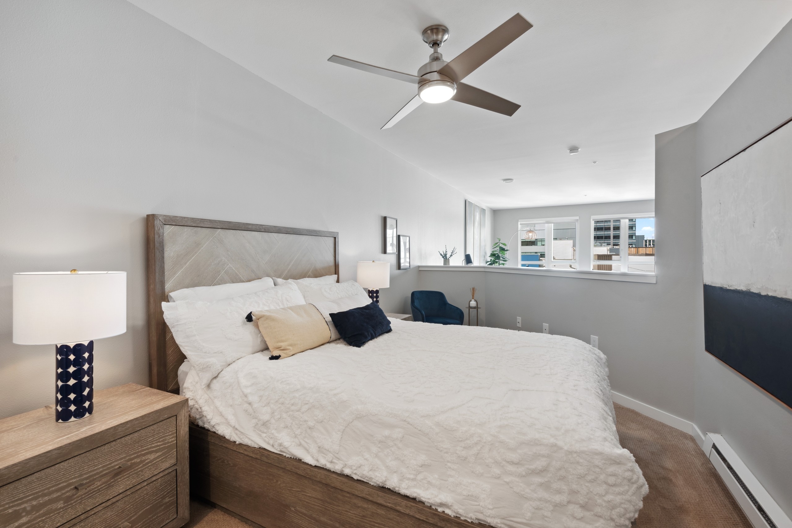 AMLI 535 bedroom with light wood bed and nightstand with while bedspread and half wall over looking view to the city