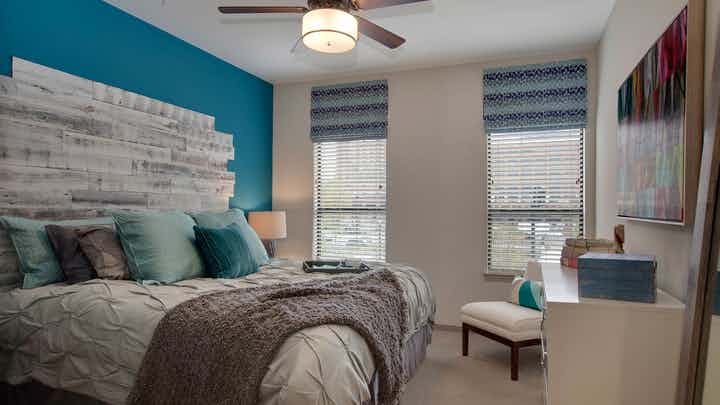 AMLI Ponce Park apartment bedroom with cream walls and carpet flooring with large windows for natural sunlight