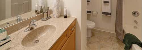 View of an AMLI 900 bathroom featuring modern maple cabinets paired with a light tan colored countertop and tile flooring