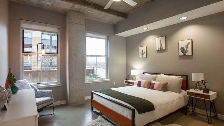 AMLI Downtown bedroom with grey walls and a comfy white bed in front of two large windows with a bright daytime view