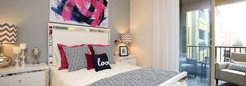 Interior Daytime view of AMLI Warner Center apartment bedroom with centered wall art above bed overlooking furnished patio