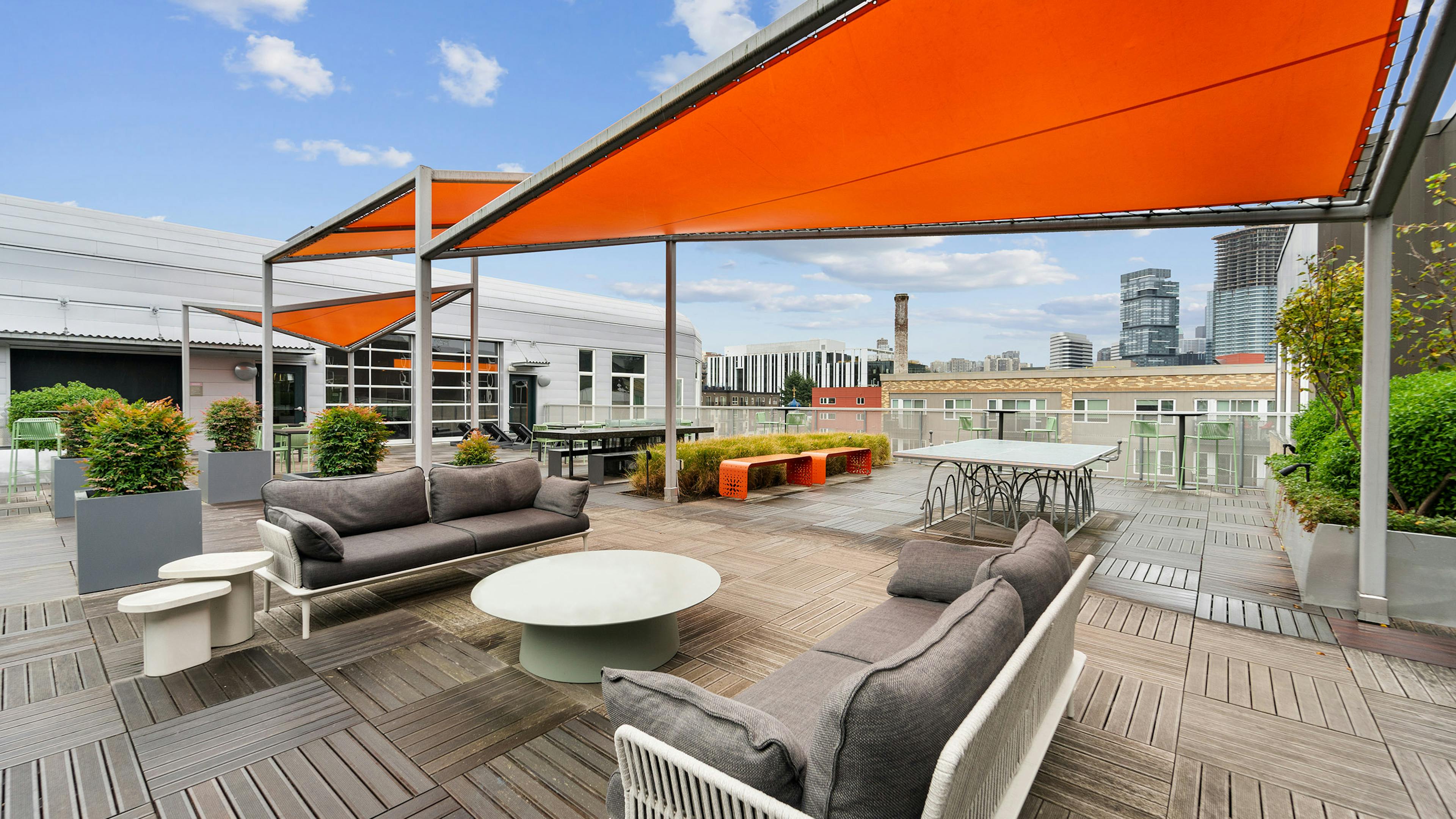 Sky deck at AMLI South Lake Union with large orange triangular canopies and seating and planters and a ping pong table