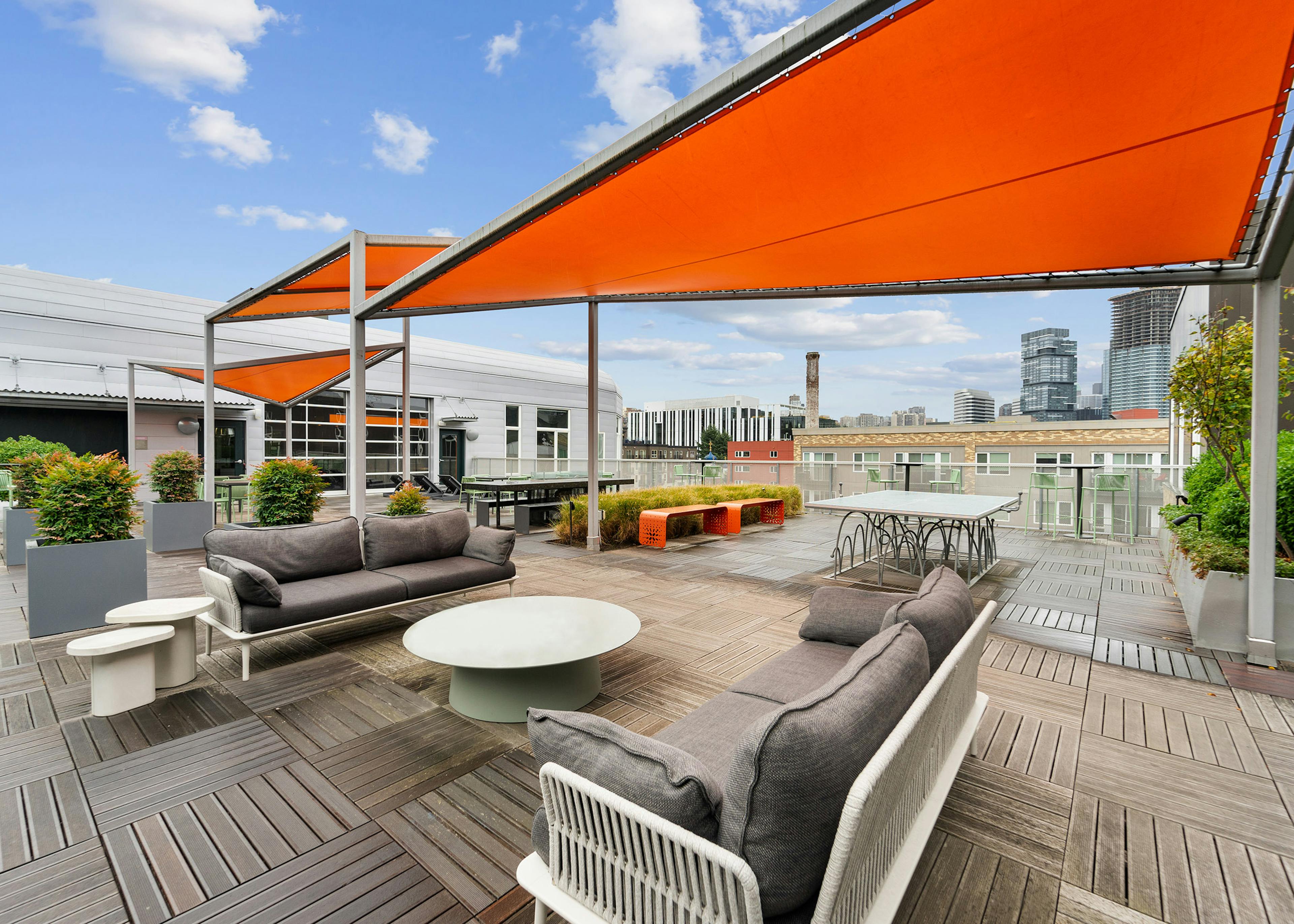 Sky deck at AMLI South Lake Union with large orange triangular canopies and seating and planters and a ping pong table