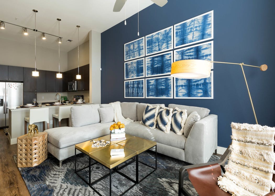 AMLI on Riverside living room with a white couch against a dark blue accent wall with patterned wall art and dark hardwood