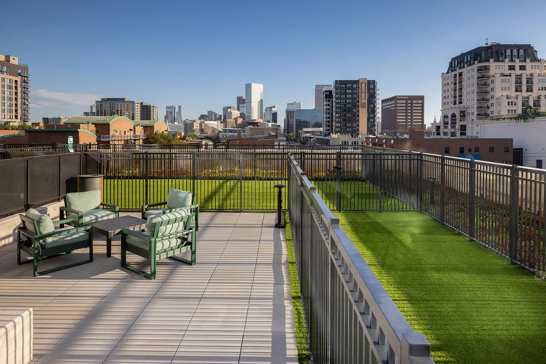 A dog park on AMLI Golden Triangle's rooftop that overlooks the Denver city skyline on a clear and sunny day