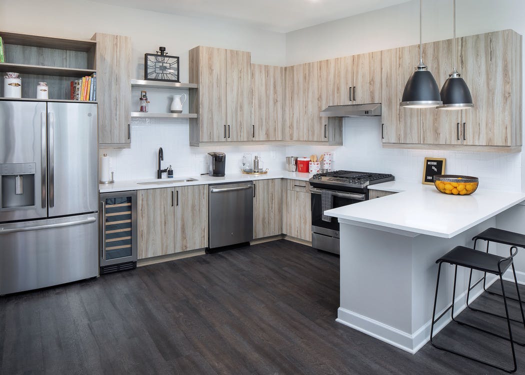 AMLI Westside kitchen with dark wood floors and modern black light fixtures hanging above barstools at counter area