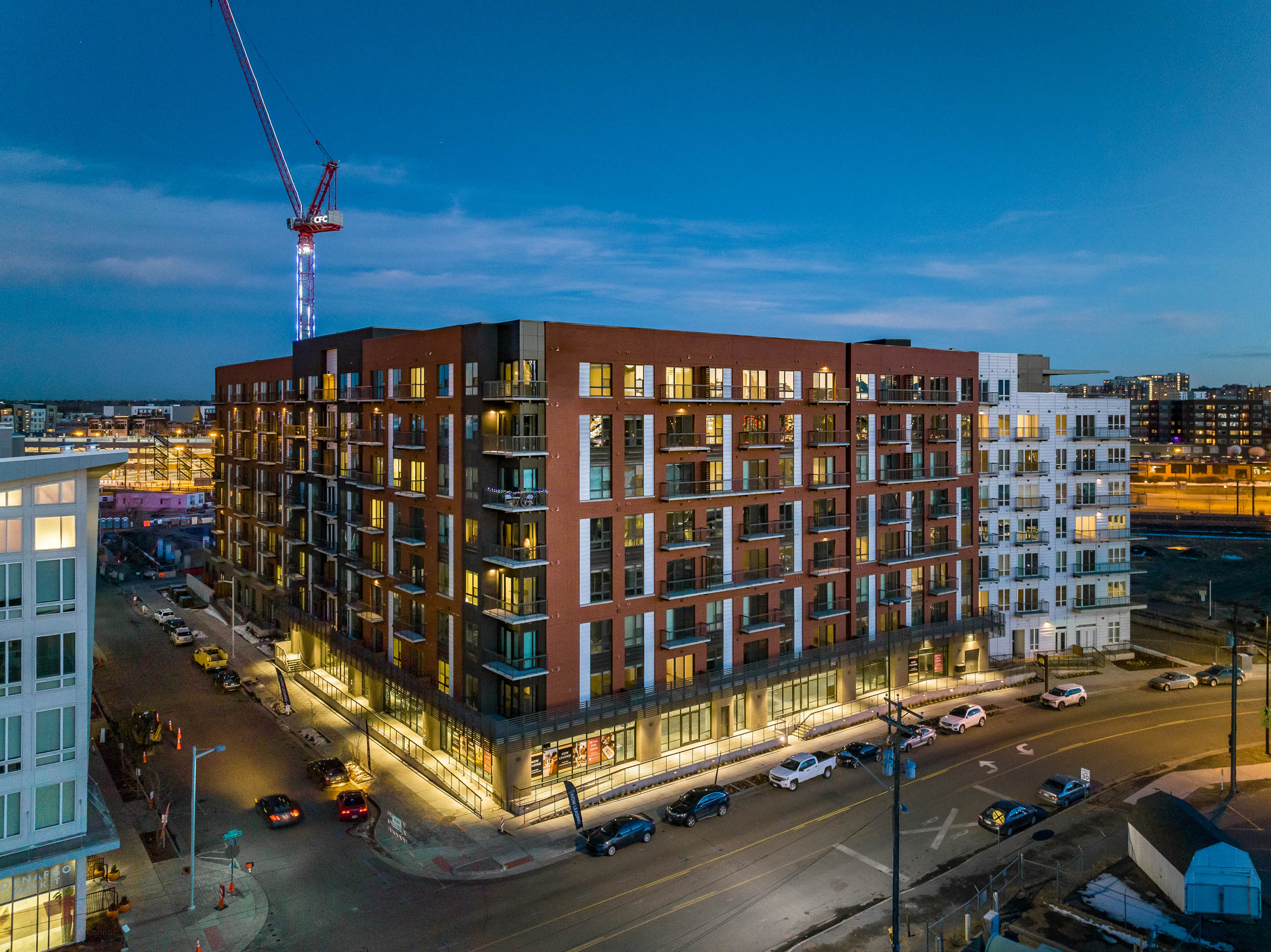 Aerial exterior view of the AMLI Art District building with cars parked along the street with light poles and dark blue sky