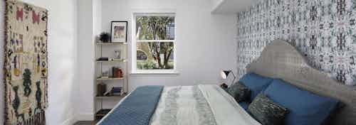 AMLI Park Broadway master bedroom with boho chic décor and designer wallpaper behind a king size bed with blue sheets