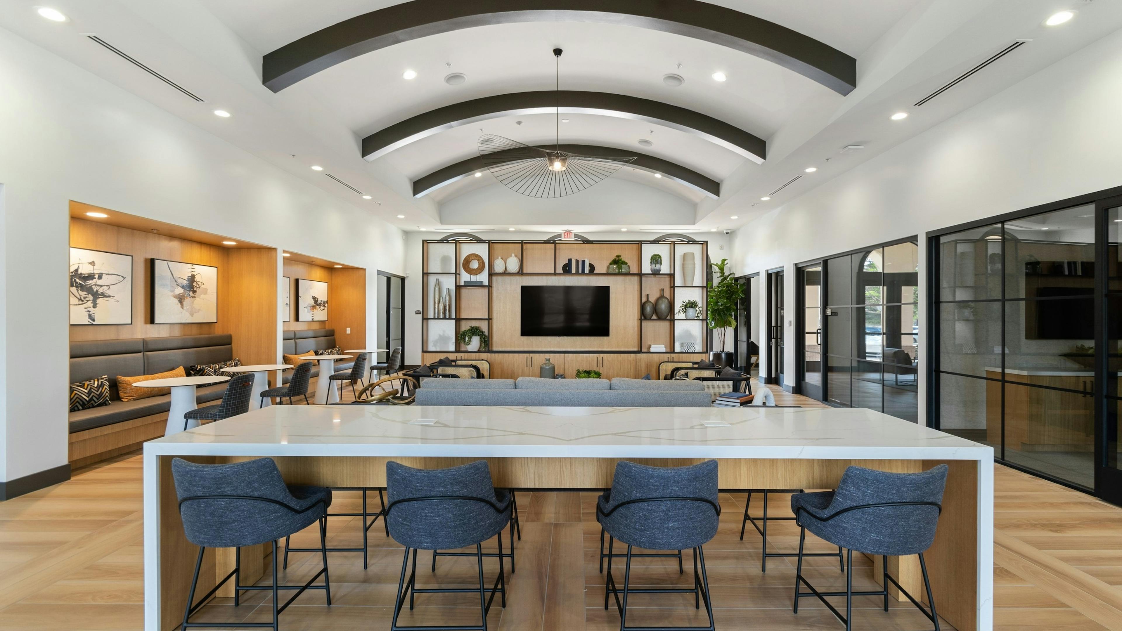 Centered view of clubhouse at AMLI Spanish Hills apartments with quartz table and blue chairs and decorative light fixture