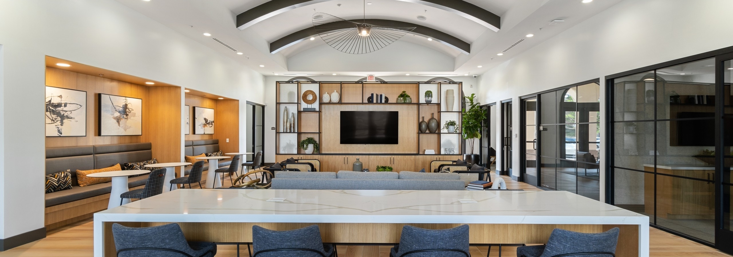 Centered view of clubhouse at AMLI Spanish Hills apartments with quartz table and blue chairs and decorative light fixture