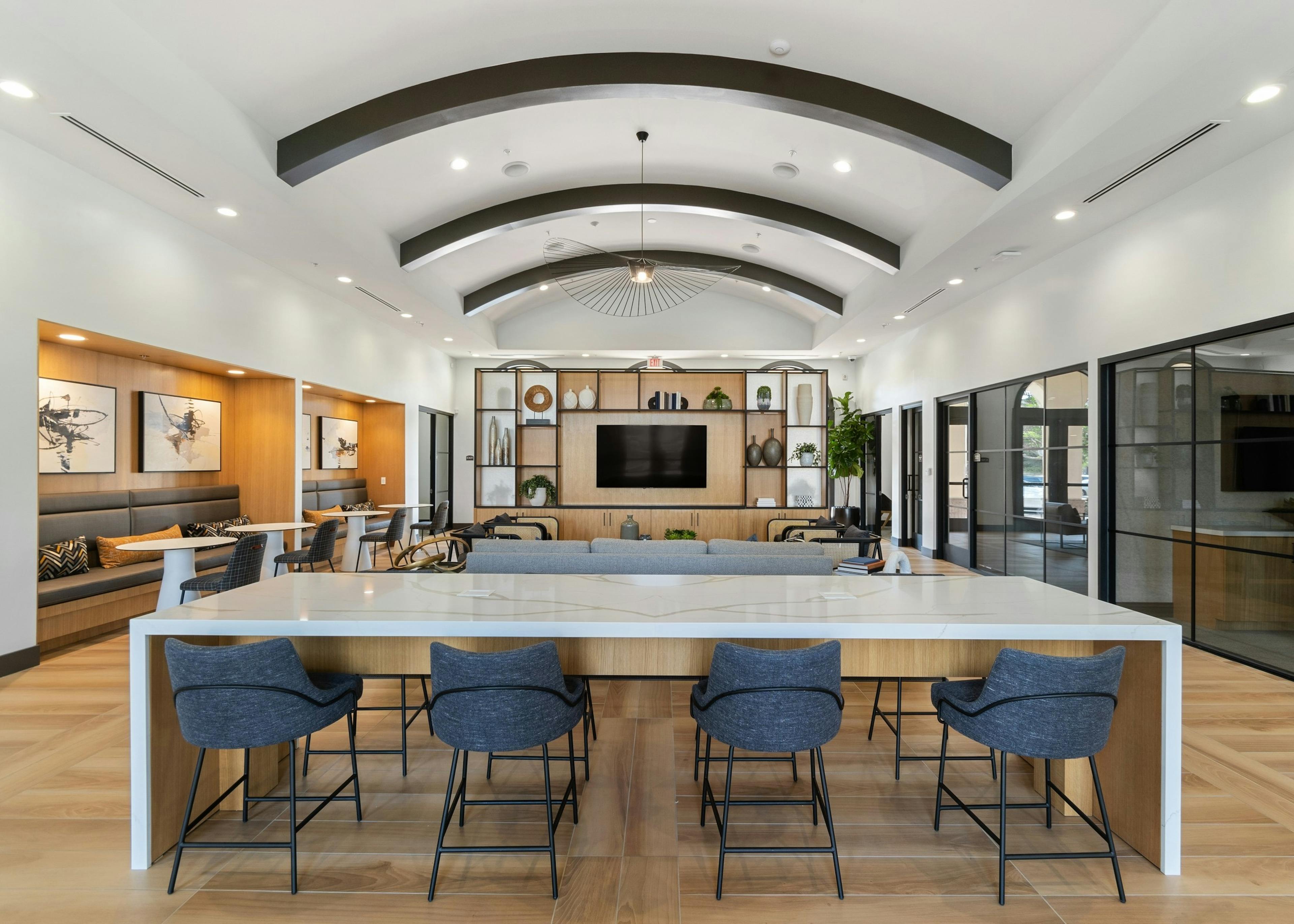 Centered view of clubhouse at AMLI Spanish Hills apartments with quartz table and blue chairs and decorative light fixture