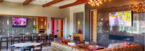Interior view of the clubroom at AMLI Denargo Market apartments with several couches and chairs and artful hanging lights